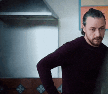 a man with a beard is standing in a kitchen
