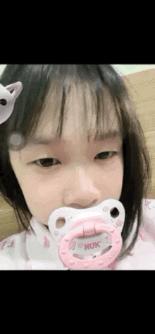 a little girl with a pacifier in her mouth .