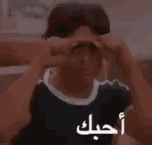 a man is making a funny face with his hands while sitting on a chair .