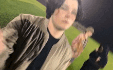 a blurry picture of a man in a bomber jacket standing on a field .