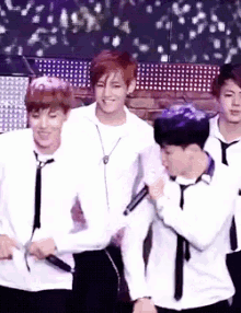 a group of young men wearing white shirts and black ties are holding microphones