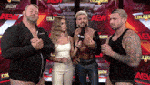a group of people standing in front of a wall that says aew on it