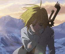 a person is holding a sword in their hand in front of a mountain range .