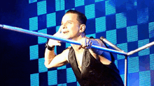 a man holding a microphone in front of a checkered wall