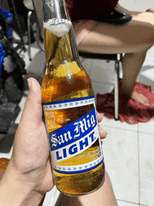 person holding a bottle of san mig light beer