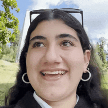 a woman wearing hoop earrings and glasses smiles for the camera