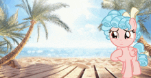 a pink and blue pony is standing on a beach