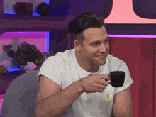 a man in a white shirt is drinking from a black coffee cup