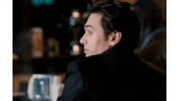 a man in a suit is sitting at a table with his back to the camera .