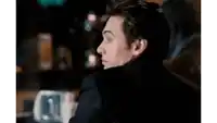 a man in a suit is sitting at a table with his back to the camera .