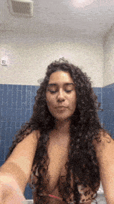 a woman with curly hair is taking a selfie in a bathtub .
