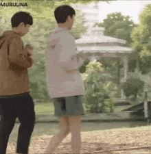 a man and a woman are standing next to each other in a park .
