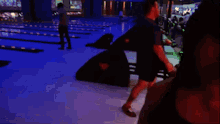 a woman in a black tank top is standing in a dark room .