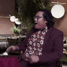 a man in a floral shirt and a purple jacket is dancing