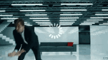 a man in a suit stands in a room with a loading circle in the background
