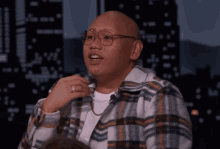 a man wearing glasses and a plaid shirt has a ring on his left hand