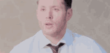 a man in a white shirt and tie is making a funny face .