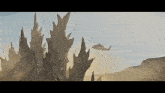 a helicopter is flying over a desert landscape with trees in the background