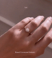 a close up of a woman 's hand with a diamond ring on it .
