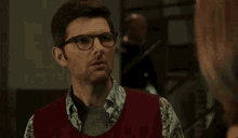 a man in a red vest is talking to a woman in a room .