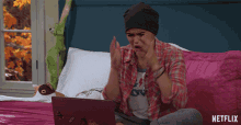 a girl sitting on a bed looking at a laptop with netflix written on the bottom