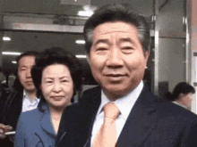 a man in a suit and tie is standing next to a woman in a blue jacket
