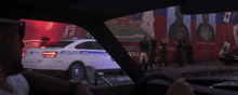 a police car is parked in front of a wall with a picture of a man