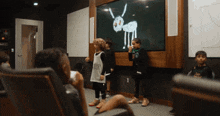 a group of children are standing in front of a drawing of an ant on a screen