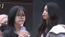 a girl with glasses is holding a bottle of water and making a face