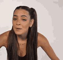 a woman with long hair and a ponytail is wearing a black tank top