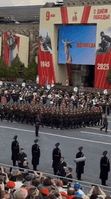 soldiers marching in front of a large screen that says 1945 and 2025