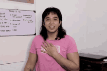 a woman in a pink shirt is standing in front of a white board that says things to do