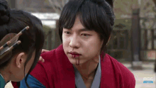 a man and a woman are looking at each other with blood on their faces .