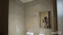a man taking a picture of himself in a bathroom mirror with the words made in animotica on the bottom