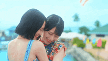 two women are hugging each other in front of a pool