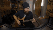 a man with a beard is playing a guitar and wearing a black shirt with the number 5 on it