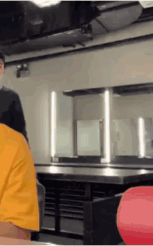 a man in a yellow shirt is sitting in a restaurant
