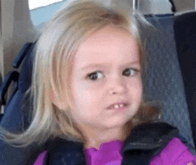 a little girl is making a funny face while sitting in a car seat on a plane .