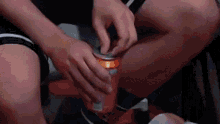 a person is opening a soda can with their hands while sitting down .