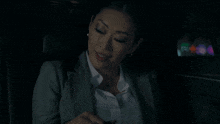 a woman in a suit is sitting in the back of a car