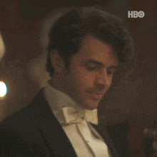 a man in a tuxedo and bow tie is standing in a dark room .