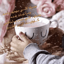 a person holding a cup of coffee with arabic writing