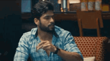 a man in a plaid shirt is sitting on a couch