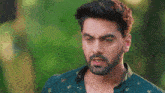 a man with a beard is wearing a green shirt and looking at something .