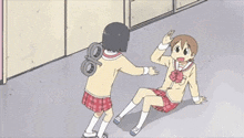 a girl with a wind up toy on her back shakes hands with another girl sitting on the floor