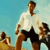 a man in a white shirt and shorts stands on a rock