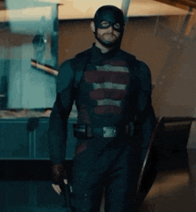 a man in a superhero costume is holding a shield and a gun