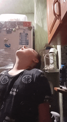 a man laying in front of a frostin fridge