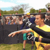a man in a yellow shirt with the letter l on it stands in front of a crowd