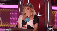 a woman making a funny face while sitting at a desk with a nbc logo on the bottom